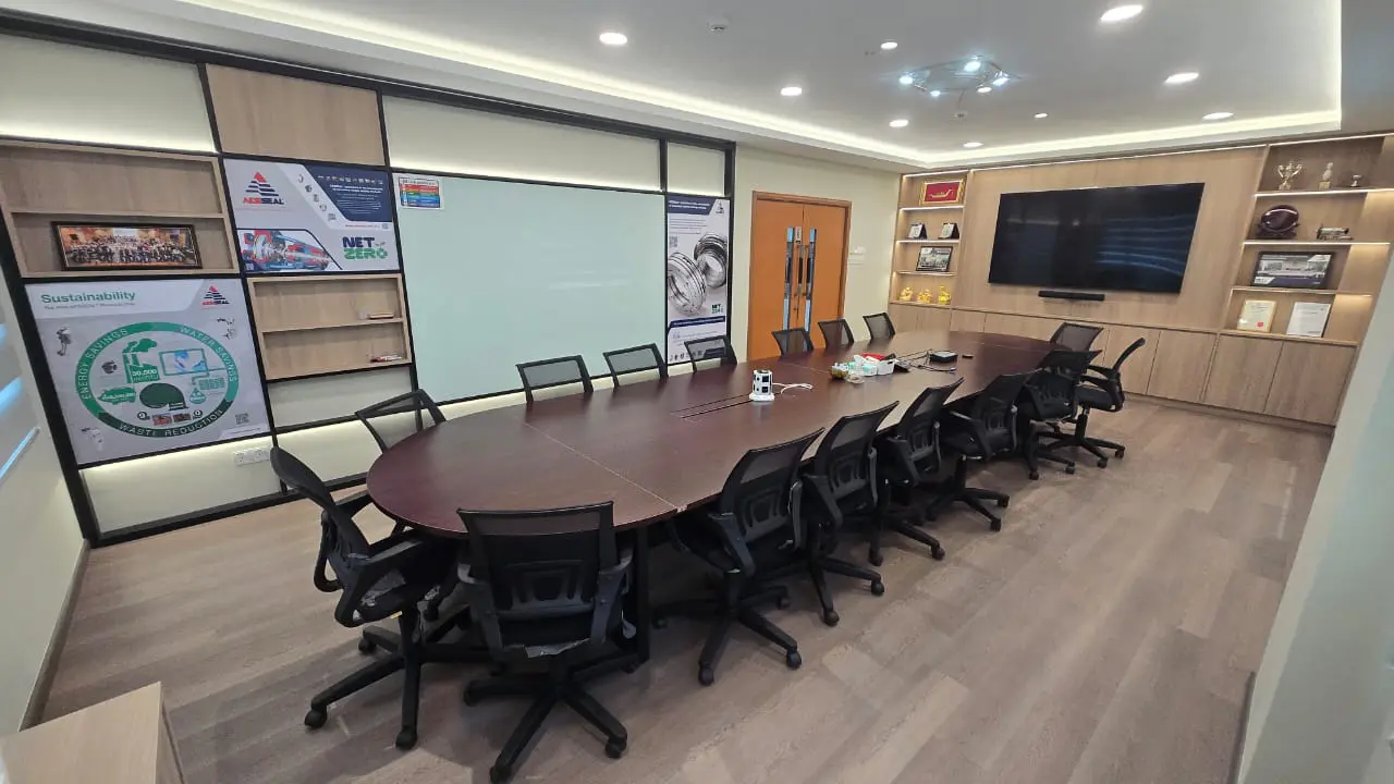Meeting room with a long wooden table, television screen and shelves holding awards.