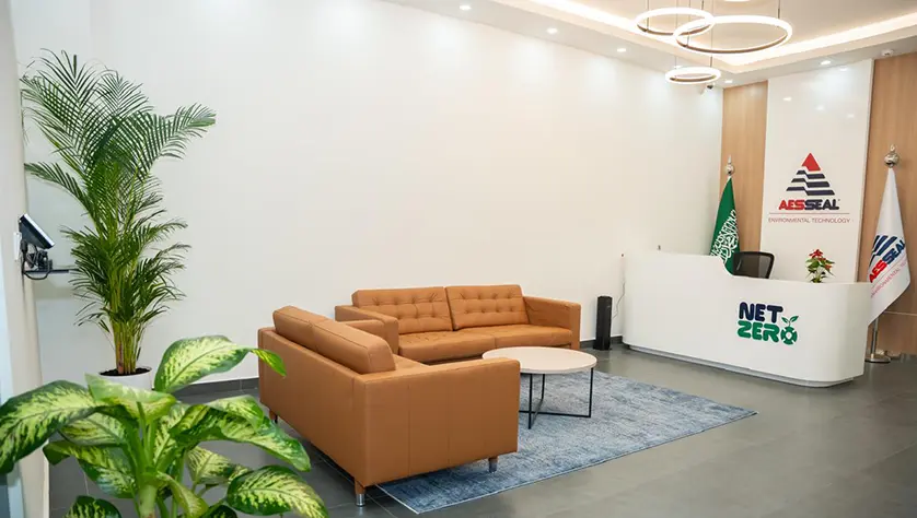Reception room with welcome desk, two sofas and plants.