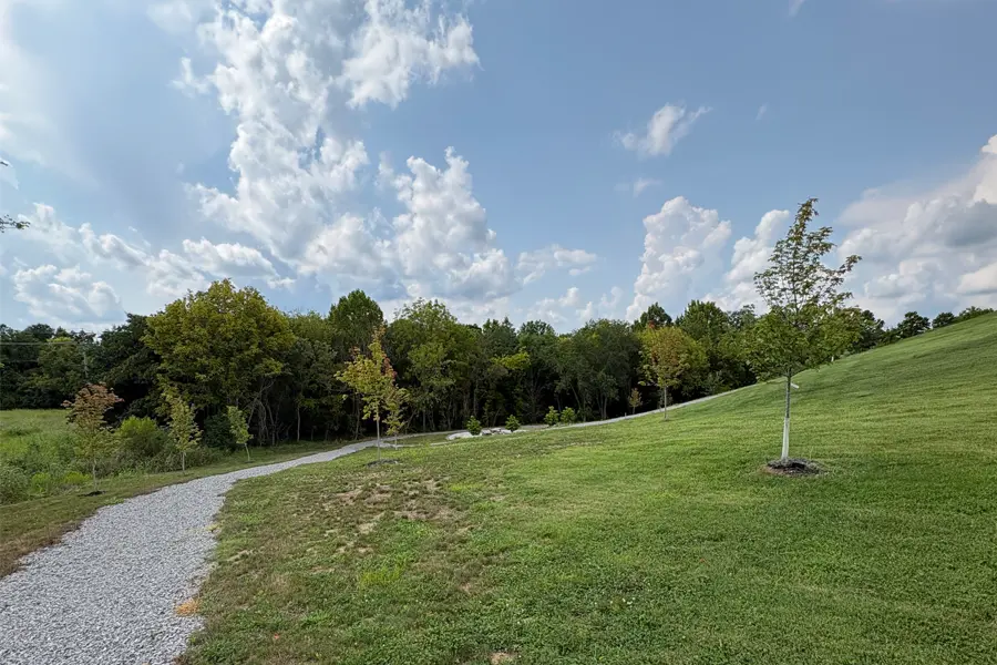 A gravel path at the bottom of a sloping, green hill.